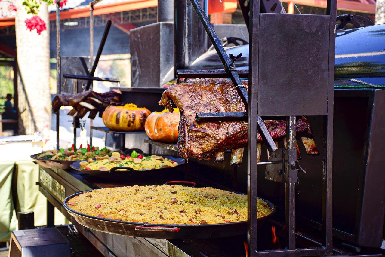 Estação de parrilla com carnes e acompanhamentos no fogo